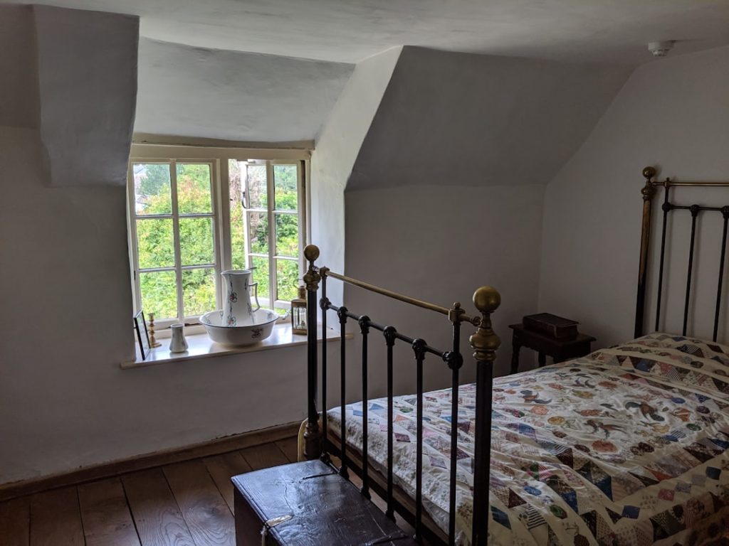 Chambre mansardée d’un gîte, lit en fer et poutres apparentes